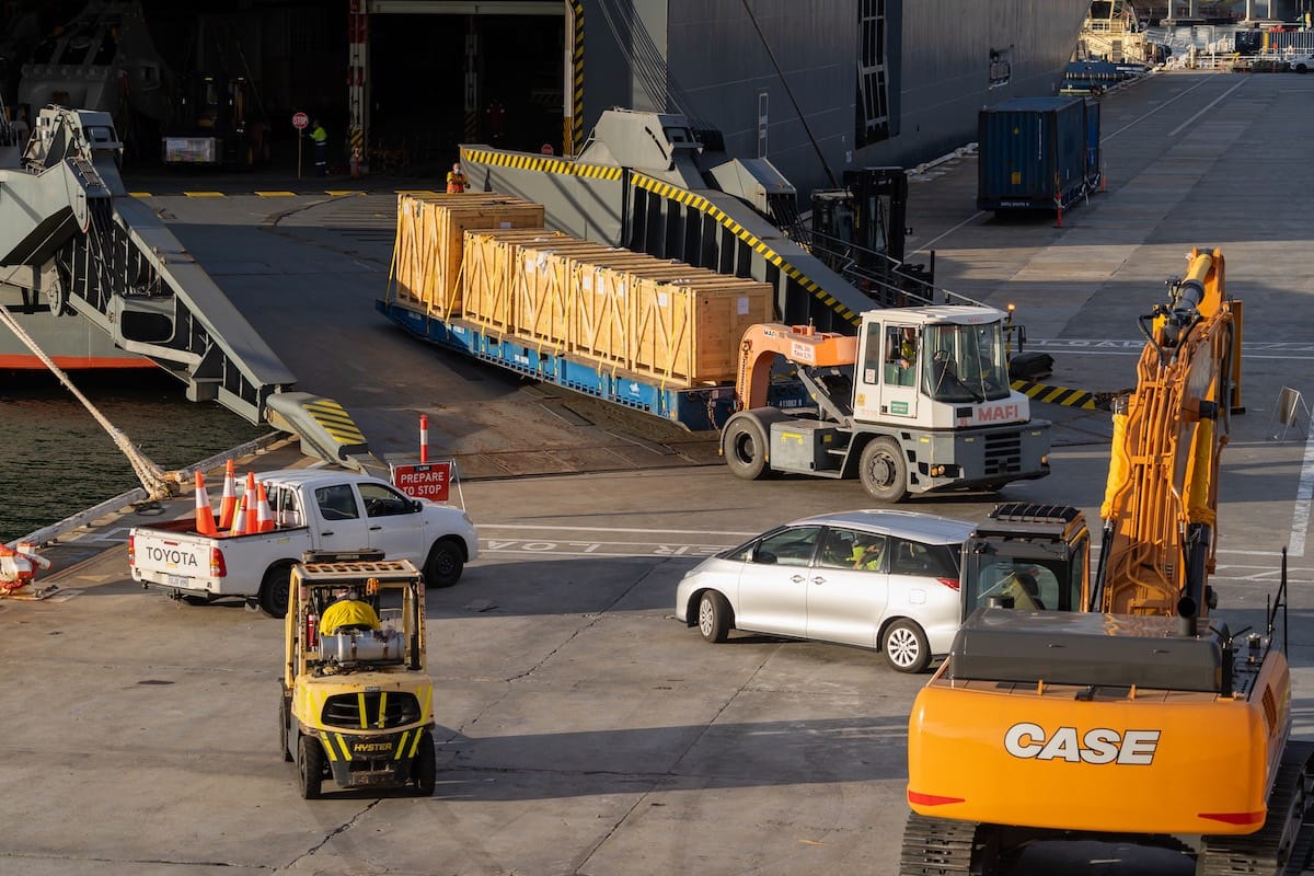 Truck driving pallets off a ship at a dock
